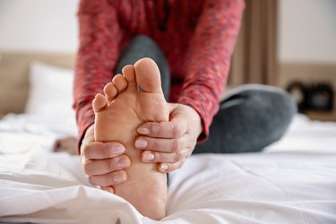 close view of a person holding her foot because she has foot arch pain