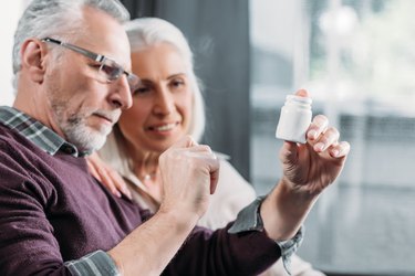 an older couple holds a supplement bottle and reads the label