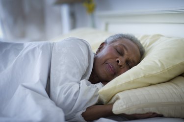 an older adult sleeping on their side in bed, to represent relief for hip pain while sleeping