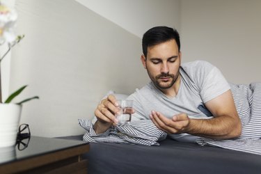 a man lying in bed and taking a natural sleep aid such as melatonin